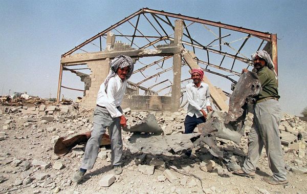 Iraqis clear away debris in front of a construction materials warehouse 12 August 2000, the morning after US and British warplanes bombed residential districts, a grain silo, the warehouse and the traffic department of the southern Iraqi city Samawa. (File) - Sputnik International