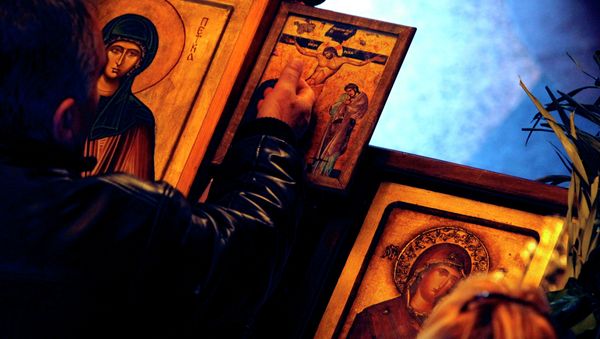 A man touches an icon with the crucifixion of Jesus Christ on Good Friday at St. Petka Orthodox church in Skopje, Macedonia A man touches an icon with the crucifixion of Jesus Christ on Good Friday at St. Petka Orthodox church in Skopje, Macedonia - Sputnik International