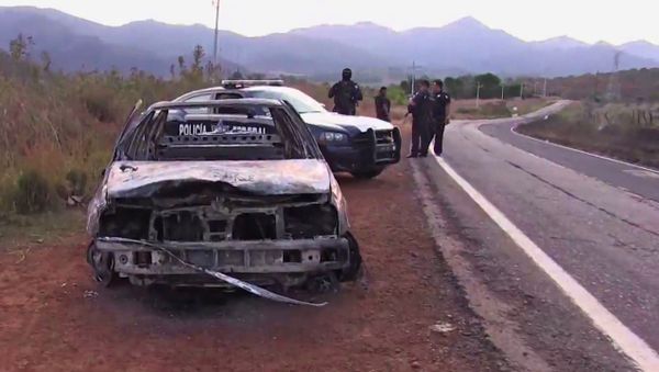 Grab taken from a video of policemen inspecting a burnt police vehicle on April 7, 2015 on a Jalisco state road, Mexico, where at least 15 police officers were killed, overnight, in an ambush carried out by a gang called Jalisco New Generation Drug Cartel.  - Sputnik International