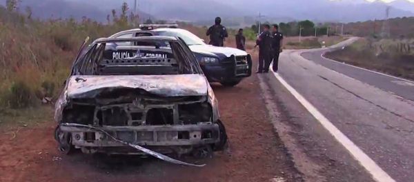 Grab taken from a video of policemen inspecting a burnt police vehicle on April 7, 2015 on a Jalisco state road, Mexico, where at least 15 police officers were killed, overnight, in an ambush carried out by a gang called Jalisco New Generation Drug Cartel. - Sputnik International
