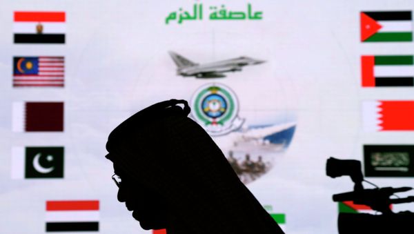 A Saudi man walks past a screen projecting images during a military briefing on the Saudi-led coalition's strikes in Yemen on Houthi rebels, in Riyadh, Saudi Arabia. - Sputnik International