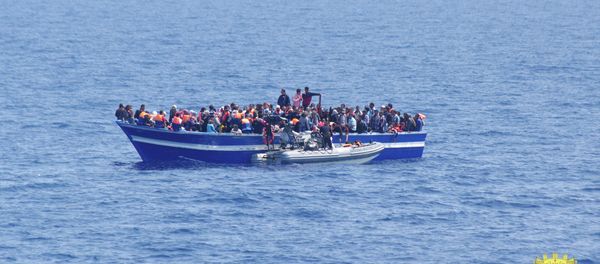 Italian Navy on Sunday, June 15, 2014, and taken on Saturday, June 14, 2014, a boat filled with migrants receives aid from an Italian Navy motor boat off the coast of Sicily, Italy. The Italian coast guard and navy have rescued more than 300 migrants. - Sputnik International