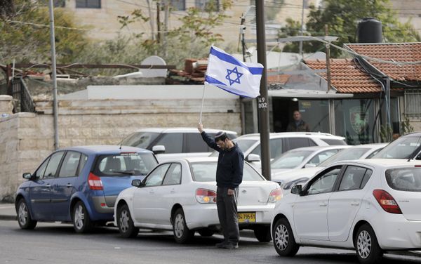 A man holds Israel's national flag as he stands still during the sounding of a two-minute siren marking Holocaust Remembrance Day in Jerusalem A man holds Israel's national flag as he stands still during the sounding of a two-minute siren marking Holocaust Remembrance Day in Jerusalem - Sputnik International