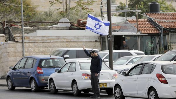 A man holds Israel's national flag as he stands still during the sounding of a two-minute siren marking Holocaust Remembrance Day in Jerusalem A man holds Israel's national flag as he stands still during the sounding of a two-minute siren marking Holocaust Remembrance Day in Jerusalem - Sputnik International