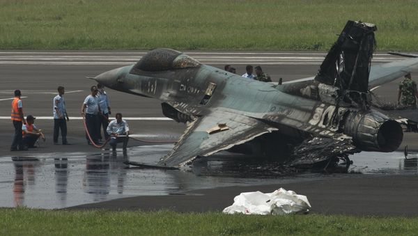 Air Force personnel spray water on an Indonesian F-16 to cool it down before moving it after it burned following an aborted take-off at Halim Air Base, East Jakarta April 16, 2015 - Sputnik International