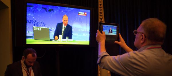 A journalist takes a picture from a TV screen while Russian President Vladimir Putin speaks during a nationally televised question-and-answer session in Moscow in Moscow, Russia, Thursday, April 16, 2015 - Sputnik International