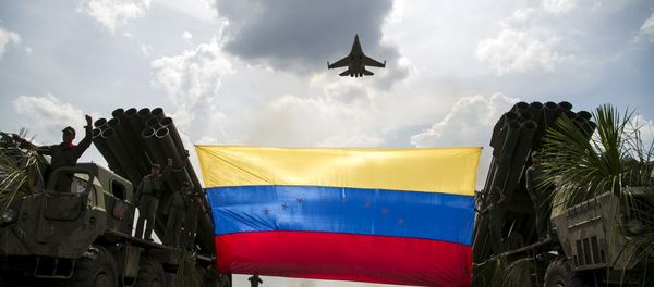 A Russian-made Sukhoi Su-30MKV fighter jet of the Venezuelan Air Force flies over a Venezuelan flag tied to missile launchers, during the Escudo Soberano 2015 (Sovereign Shield 2015) military exercise in San Carlos del Meta in the state of Apure - Sputnik International
