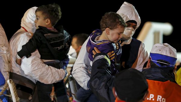 Children are carried by rescue workers as migrants arrive via boat at the Sicilian harbor of Pozzallo Children are carried by rescue workers as migrants arrive via boat at the Sicilian harbor of Pozzallo - Sputnik International