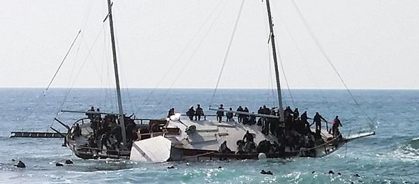 Migrants, who are trying to reach Greece, are seen onboard a capsized sailboat, as others are seen in the water trying to reach the coast of the southeastern island of Rhodes April 20, 2015 Migrants, who are trying to reach Greece, are seen onboard a capsized sailboat, as others are seen in the water trying to reach the coast of the southeastern island of Rhodes April 20, 2015 - Sputnik International