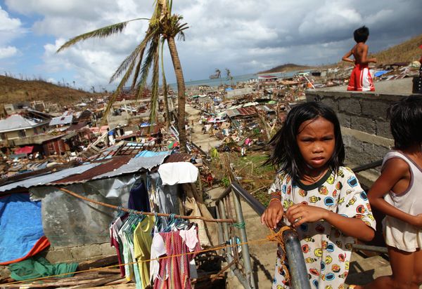Filipino children play as houses damaged by Typhoon Haiyan are seen in the background in Marabut, Philippines in 2013. - Sputnik International