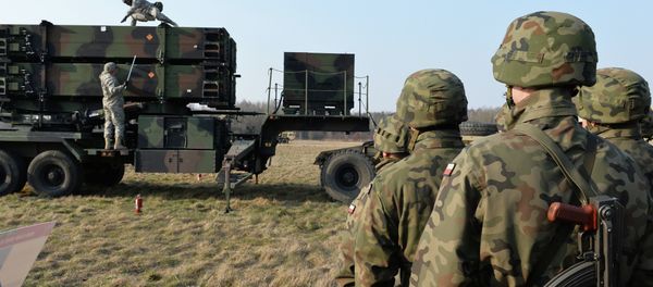 Polish soldiers watch as US troops from the 5th Battalion of the 7th Air Defense Regiment emplace a launching station of the Patriot air and missile defence system at a test range in Sochaczew, Poland, on March 21, 2015. - Sputnik International