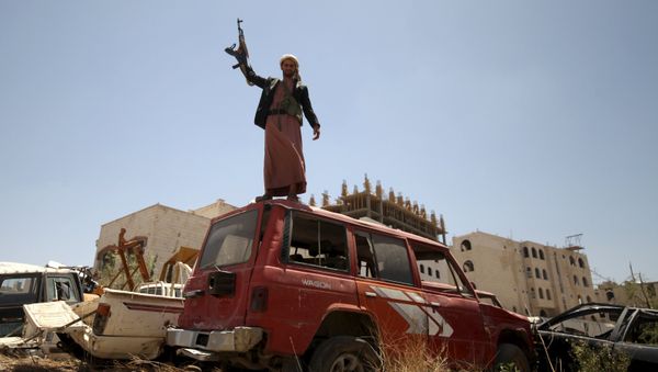 A follower of the Houthi group raises his weapon as he stands on a vehicle on a damaged street, caused by an April 20 air strike that hit a nearby army weapons depot, in Sanaa April 21, 2015 A follower of the Houthi group raises his weapon as he stands on a vehicle on a damaged street, caused by an April 20 air strike that hit a nearby army weapons depot, in Sanaa April 21, 2015 - Sputnik International
