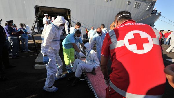 Rescuers take care of an immigrant, part of a group of more than 1,370 people, after he disembarked from the Italian military ship San Giusto on August 25, 2014 in the port of Crotone, southern Italy, following the Mare Nostrum rescue operations at sea Rescuers take care of an immigrant, part of a group of more than 1,370 people, after he disembarked from the Italian military ship San Giusto on August 25, 2014 in the port of Crotone, southern Italy, following the Mare Nostrum rescue operations at sea - Sputnik International