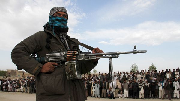 A member of the Taliban insurgent and other people stand at the site during the execution of three men in Ghazni Province on April 18, 2015. A member of the Taliban insurgent and other people stand at the site during the execution of three men in Ghazni Province on April 18, 2015. - Sputnik International