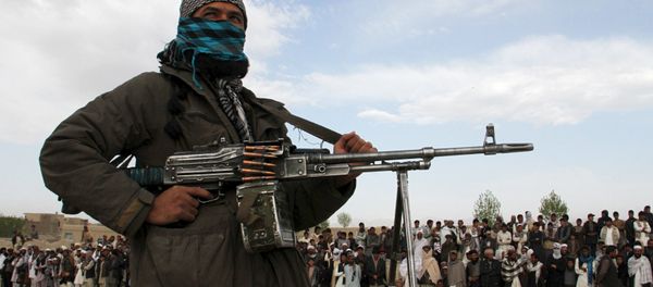 A member of the Taliban insurgent and other people stand at the site during the execution of three men in Ghazni Province on April 18, 2015. A member of the Taliban insurgent and other people stand at the site during the execution of three men in Ghazni Province on April 18, 2015. - Sputnik International