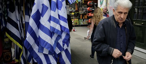 A man walk past a kiosk with Greek flags for sale in central Athens. A man walk past a kiosk with Greek flags for sale in central Athens. - Sputnik International