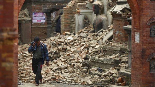 A man cries as he walks on the street while passing through a damaged statue of Lord Buddha a day after an earthquake in Bhaktapur, Nepal A man cries as he walks on the street while passing through a damaged statue of Lord Buddha a day after an earthquake in Bhaktapur, Nepal - Sputnik International