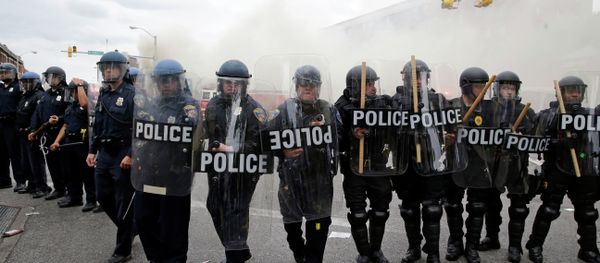 Police advance toward protestors as a store burns, Monday, April 27, 2015, during unrest following the funeral of Freddie Gray in Baltimore. - Sputnik International