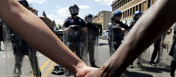 Members of the community hold hands in front of police officers in riot gear outside a recently looted and burned CVS store in Baltimore, Maryland, United States April 28, 2015 Members of the community hold hands in front of police officers in riot gear outside a recently looted and burned CVS store in Baltimore, Maryland, United States April 28, 2015 - Sputnik International
