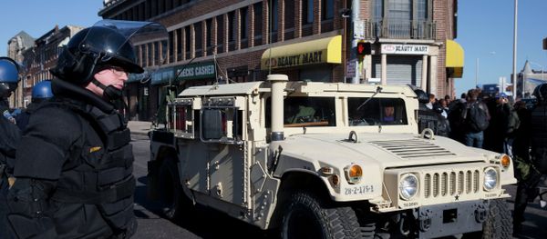 A National Guard vehicle drives by a Maryland State Trooper Tuesday, April 28, 2015, in the aftermath of rioting following Monday's funeral for Freddie Gray. - Sputnik International