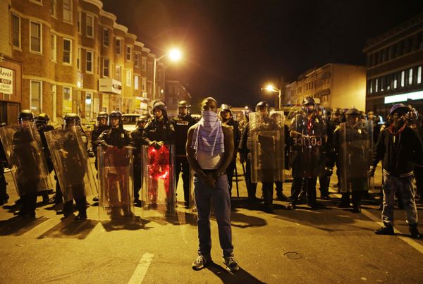 A man stands in front of a line of police officers in riot gear as part of a community effort to disperse the crowd ahead of a 10 p.m. curfew in the wake of Monday's riots following the funeral for Freddie Gray, Tuesday, April 28, 2015, in Baltimore.  - Sputnik International