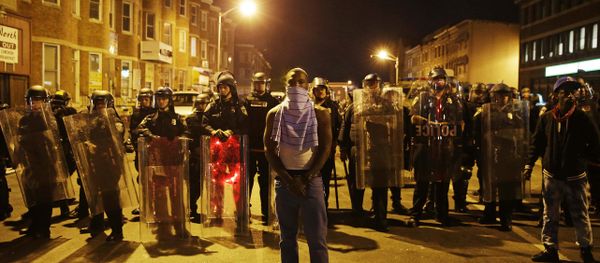 A man stands in front of a line of police officers in riot gear as part of a community effort to disperse the crowd ahead of a 10 p.m. curfew in the wake of Monday's riots following the funeral for Freddie Gray, Tuesday, April 28, 2015, in Baltimore. - Sputnik International
