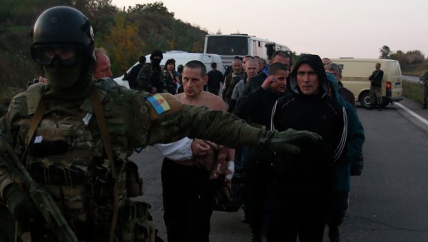 An Ukrainian soldier guards members of the Pro-Russian forces, who are prisoners-of-war, during prisoners exchange near the town of Donetsk, eastern Ukraine, Sunday, Sept. 28, 2014 - Sputnik International