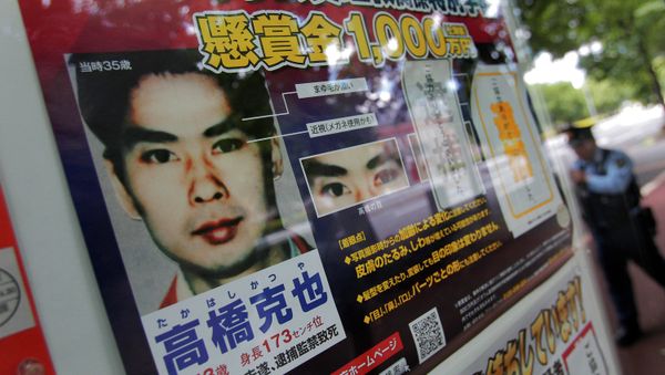 A police officer walks near a wanted poster of former Aum Shinrikyo cult member Katsuya Takahashi displayed at the metropolitan police department in Tokyo - Sputnik International