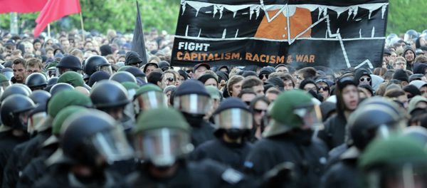 Protesters hold a banner reading ' Stop G7 - Fight Capitalism, Racism and War' as they take part in the 'Revolutionary' May Day demonstration in Berlin's Kreuzberg district on May 1, 2015 - Sputnik International