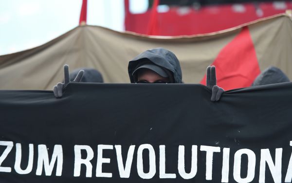 A protester shows the victory sign as he marches with a banner promoting a social revolution worldwide as he takes part in the 'Revolutionary' May Day demonstration in Berlin on May 1, 2015. A protester shows the victory sign as he marches with a banner promoting a social revolution worldwide as he takes part in the 'Revolutionary' May Day demonstration in Berlin on May 1, 2015. - Sputnik International