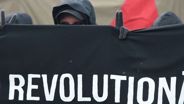 A protester shows the victory sign as he marches with a banner promoting a social revolution worldwide as he takes part in the 'Revolutionary' May Day demonstration in Berlin on May 1, 2015. - Sputnik International