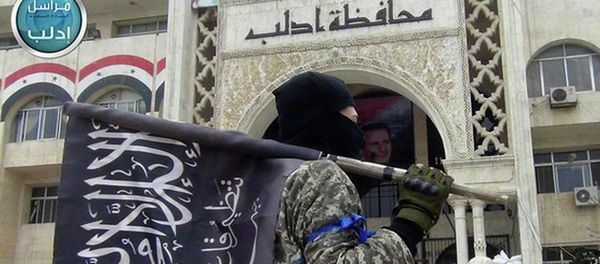 A fighter from Syria's al-Qaida-linked Nusra Front holds his group flag as he stands in front of the governor building in Idlib province, north Syria. A fighter from Syria's al-Qaida-linked Nusra Front holds his group flag as he stands in front of the governor building in Idlib province, north Syria. - Sputnik International