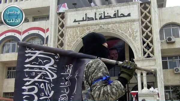 A fighter from Syria's al-Qaida-linked Nusra Front holds his group flag as he stands in front of the governor building in Idlib province, north Syria. A fighter from Syria's al-Qaida-linked Nusra Front holds his group flag as he stands in front of the governor building in Idlib province, north Syria. - Sputnik International