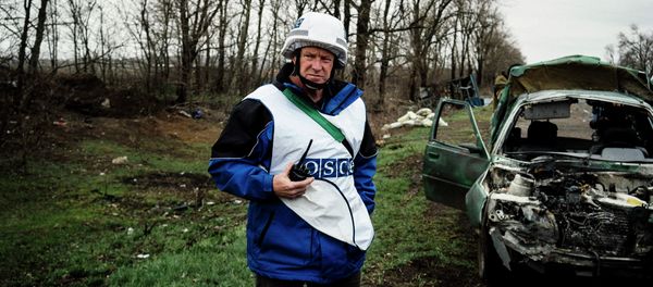 An International observer of the Organization for Security and Co-operation in Europe (OSCE) stands next to a destroyed car after shelling during an inspection tour near the village of Shirokino, near the eastern Ukrainian port city of Mariupol An International observer of the Organization for Security and Co-operation in Europe (OSCE) stands next to a destroyed car after shelling during an inspection tour near the village of Shirokino, near the eastern Ukrainian port city of Mariupol - Sputnik International