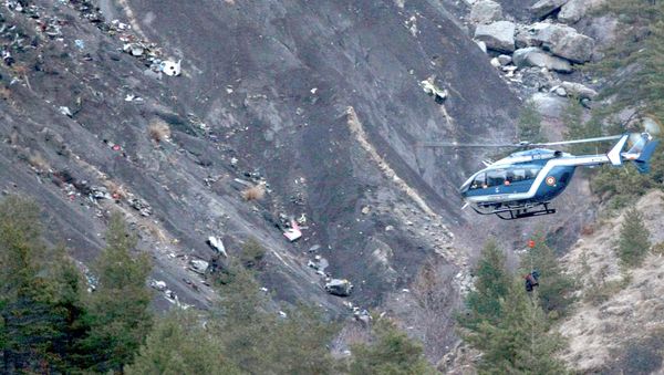 A rope hangs from a rescue helicopter flying past debris of the Germanwings passenger jet, scattered on the mountainside, near Seyne les Alpes, French Alps - Sputnik International