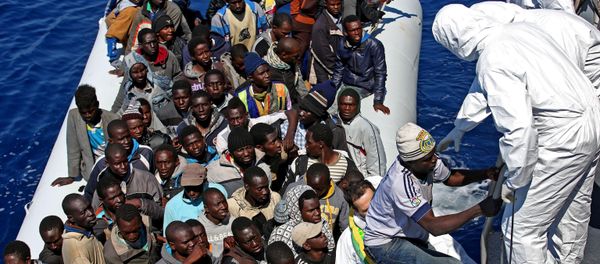 Migrants crowd and inflatable dinghy as rescue vassel  Denaro  of the Italian Coast Guard approaches them, off the Libyan coast, in the Mediterranean Sea, Wednesday, April 22, 2015 - Sputnik International