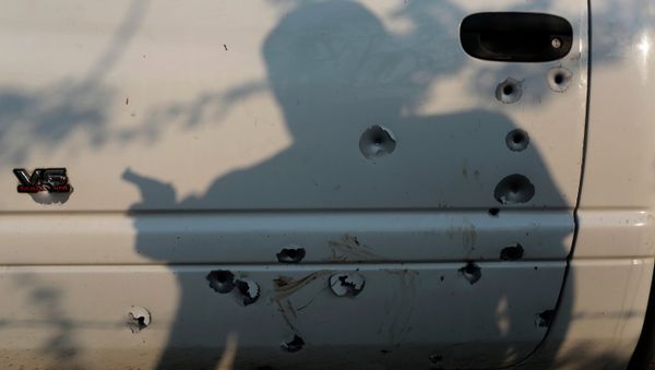 The shadow of a member of the United Front for Security and Development of the State of Guerrero (FUSDEG) vigilante group is seen before a bullet-riddled truck March 31, 2015 at San Juan del Reparo, Guerrero State, Mexico - Sputnik International