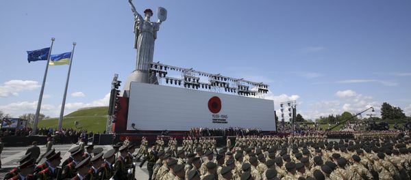 Ukrainian servicemen marching before the Mother Motherland monument in Kiev, with a Ukrainian and European Union flag fluttering in the background. - Sputnik International