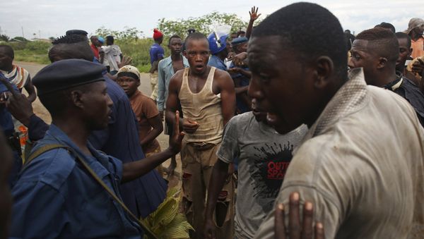 Protesters gesture near female police officer accused of shooting a protestor in Buterere neighbourhood of Bujumbura, Burundi - Sputnik International