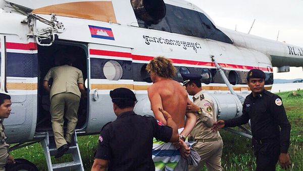 Russian Sergei Polonsky (C) is escorted by Cambodian police officials into a helicopter on an island in Preah Sihanouk province on May 15, 2015 Russian Sergei Polonsky (C) is escorted by Cambodian police officials into a helicopter on an island in Preah Sihanouk province on May 15, 2015 - Sputnik International