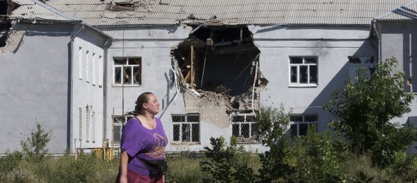 A woman walks past a damaged school in the city of Lisichansk, Luhansk region, eastern Ukraine - Sputnik International