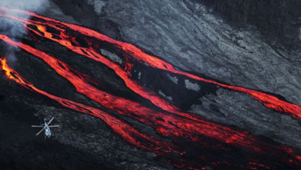 A helicopter flies overhead as lava flows out of the Piton de la Fournaise volcano - Sputnik International