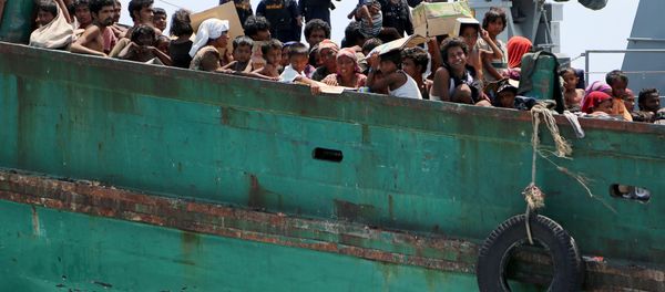 Navy officers look at migrants on their boat being towed away from Thailand by a Thai navy vessel, in waters near Koh Lipe island May 16, 2015 - Sputnik International