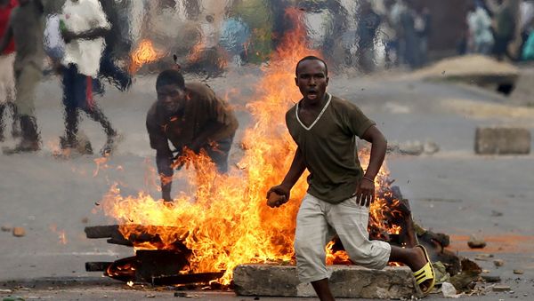 A protester runs in front of a burning barricade during a protest against Burundi President Pierre Nkurunziza and his bid for a third term in Bujumbura, Burundi, May 21, 2015 A protester runs in front of a burning barricade during a protest against Burundi President Pierre Nkurunziza and his bid for a third term in Bujumbura, Burundi, May 21, 2015 - Sputnik International