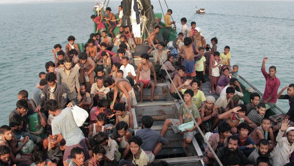 In this Wednesday, May 20, 2015 file photo, migrants wait to be be rescued by Acehnese fishermen on their boat on the sea off East Aceh, Indonesia - Sputnik International
