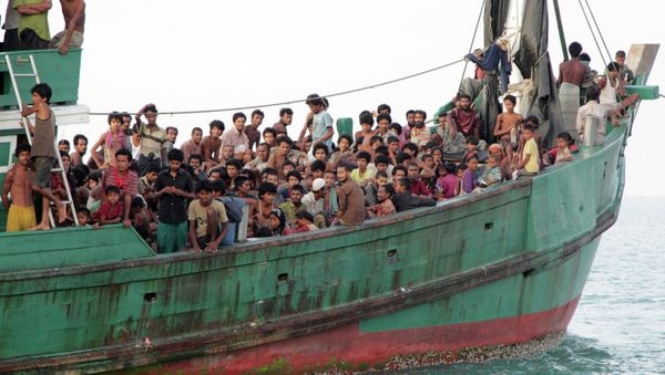 May 20, 2015 file photo, migrants sit on their boat as they wait to be rescued by Acehnese fishermen on the sea off East Aceh, Indonesia - Sputnik International