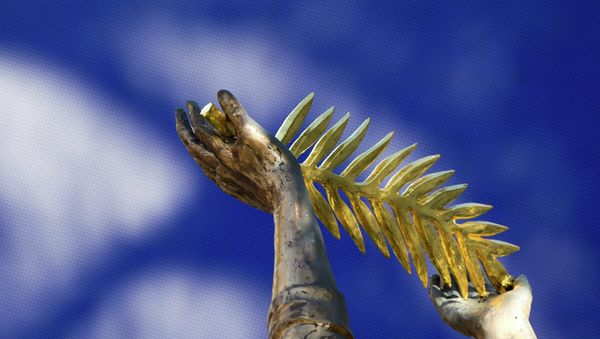 A Palme d'Or symbol is holding by a Golden Angel statue, commemorating the 100th anniversary of the WW1, outside the Carlton Hotel before the start of the 68th Cannes Film Festival in Cannes, southern France - Sputnik International