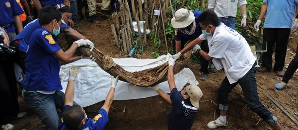 Rescue workers and forensic officials dig out skeletons from shallow graves - Sputnik International