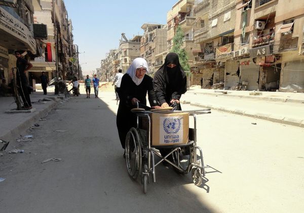Residents of Syria's Yarmuk Palestinian refugee camp, south of Damascus, use a wheelchair to carry a box of goods distributed by the United Nations Relief and Works Agency (UNRWA) on July 17, 2014 Residents of Syria's Yarmuk Palestinian refugee camp, south of Damascus, use a wheelchair to carry a box of goods distributed by the United Nations Relief and Works Agency (UNRWA) on July 17, 2014 - Sputnik International