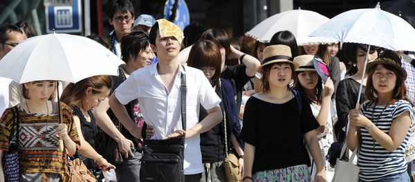 People wait for a green light at a crossing as they use umbrellas and hats to shade themselves from the sunshine in Tokyo - Sputnik International